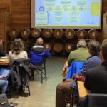 Man presents to audience of business people, timeline on screen.