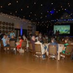 large room with people on stage and audience sitting at tables