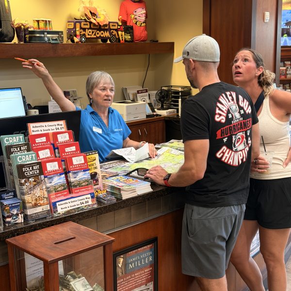 Woman at information desks gives directions to two visitors.